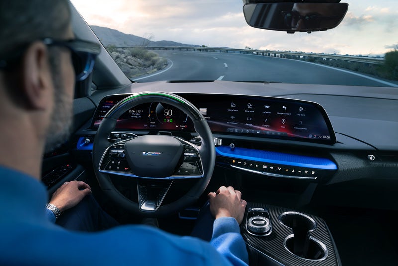 Front View of the 2026 OPTIQ-V Driving Through the Dusk Utilizing its Headlights | Sapaugh Cadillac in Herculaneum MO