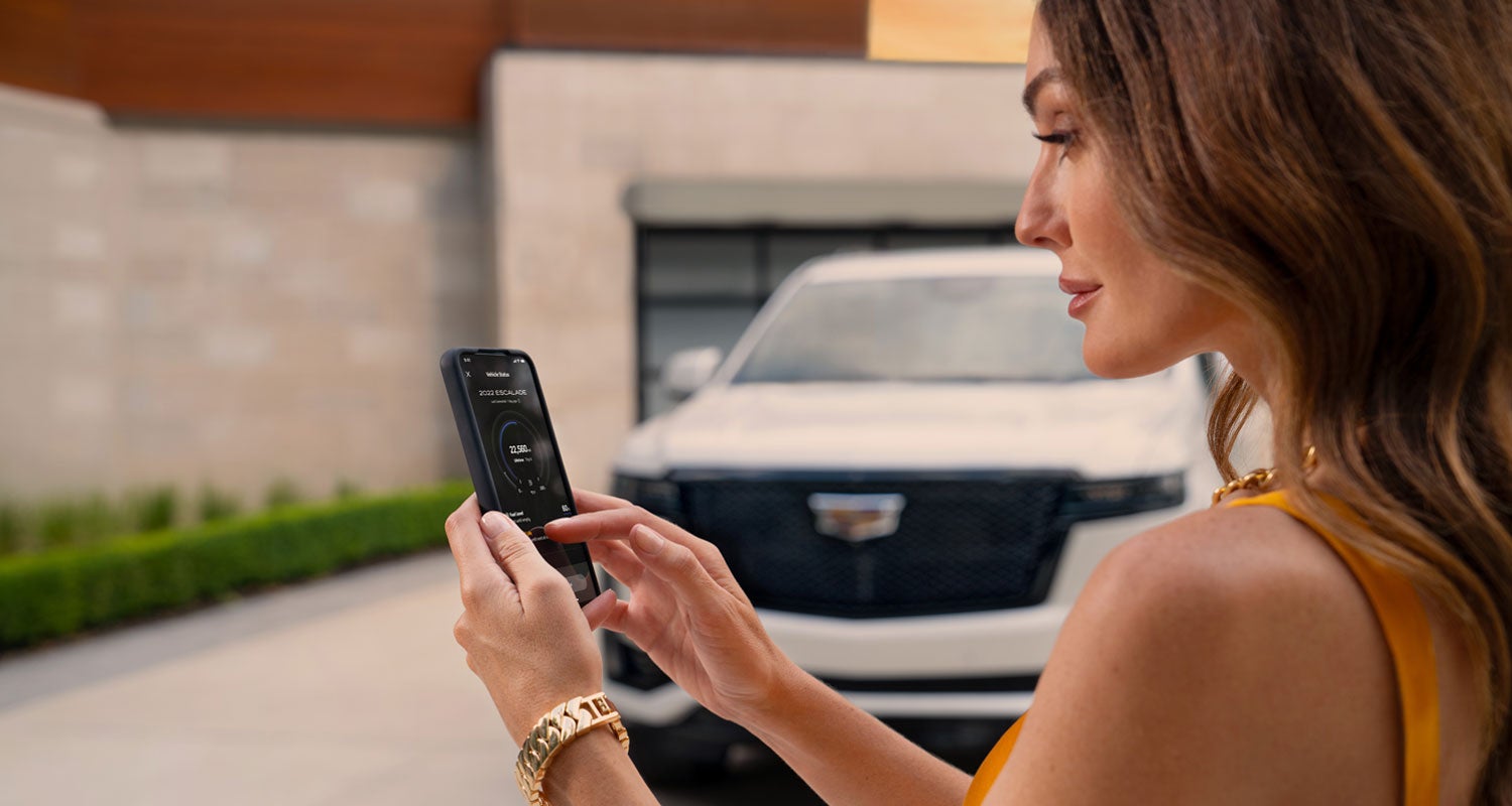lady checking her mobile with a Cadillac vehicle background | Sapaugh Cadillac in Herculaneum MO